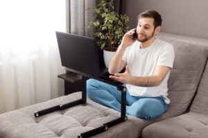 Employee taking a call while sitting in bed using laptop