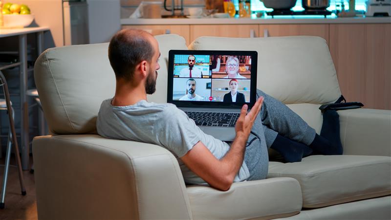 Tired man sititng at sofa using laptop